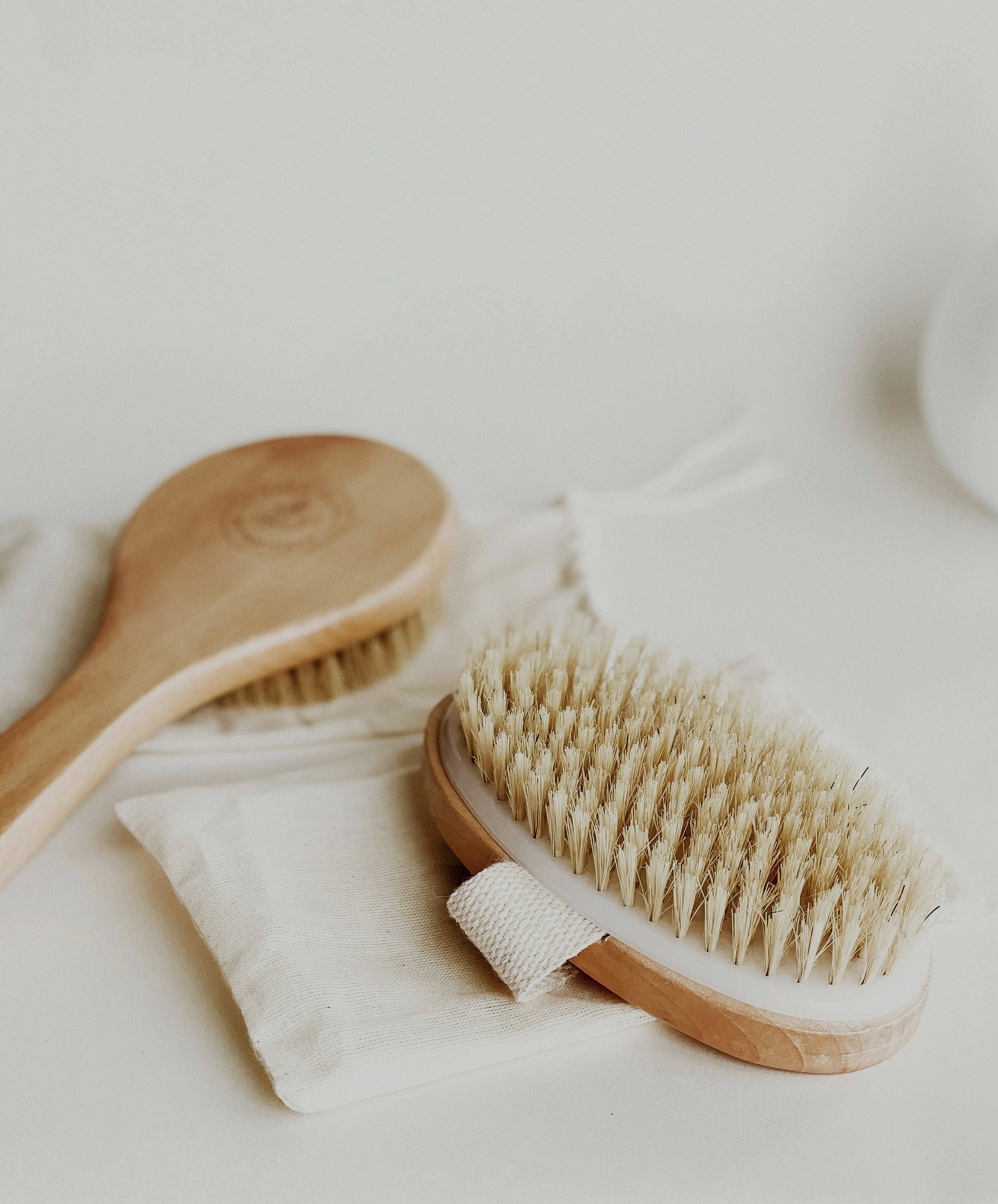 A natural dry brush and a small bottle of oil on a folded linen cloth, simple flat lay