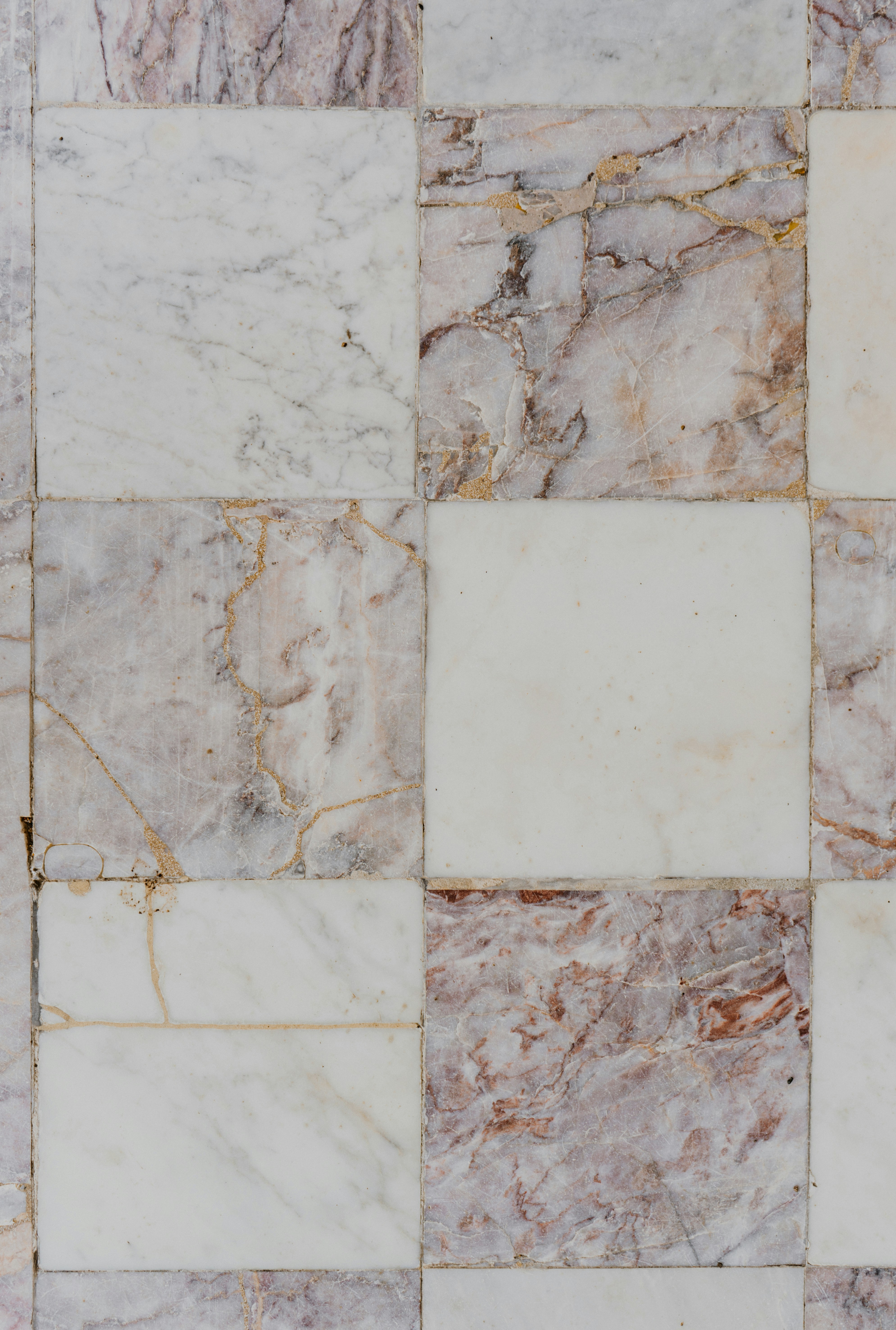 Close-up of a natural terracotta or stone tile surface, warm earthy tones, natural light raking across the texture