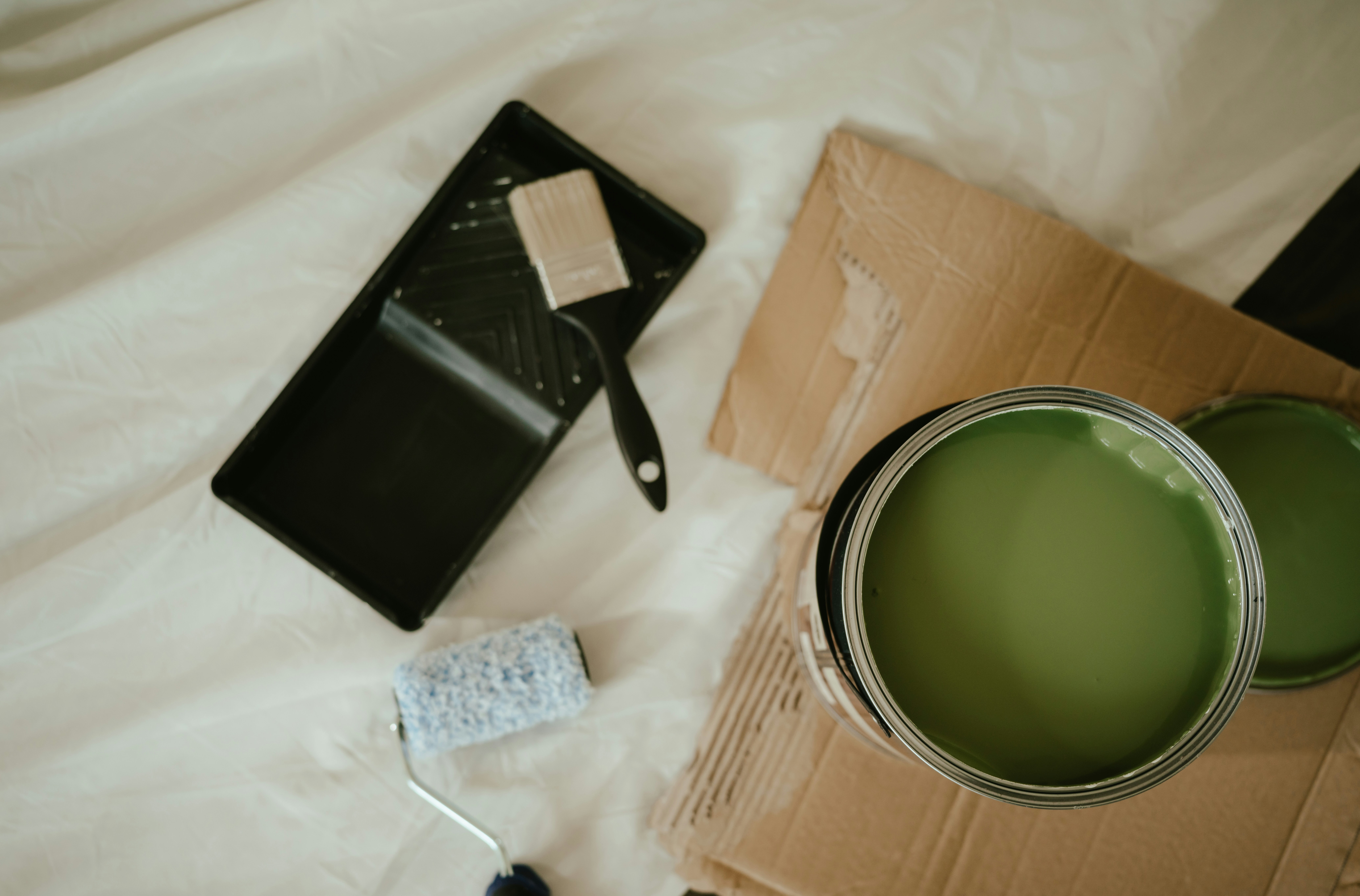 A wall mid-painting with a natural bristle brush, pale neutral paint, soft natural light from a window