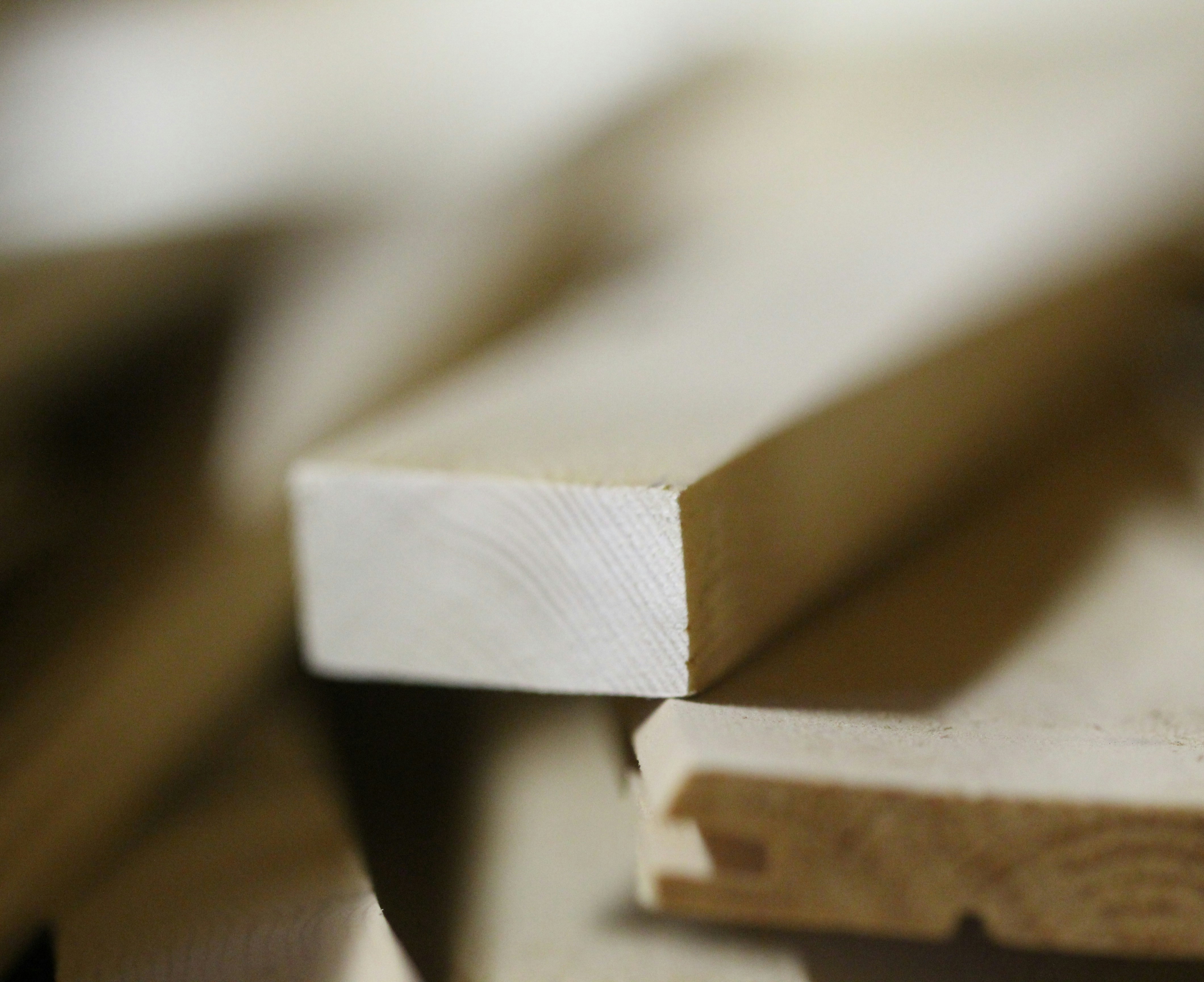 Stack of rough-cut timber planks showing natural wood grain and end grain, warm natural light