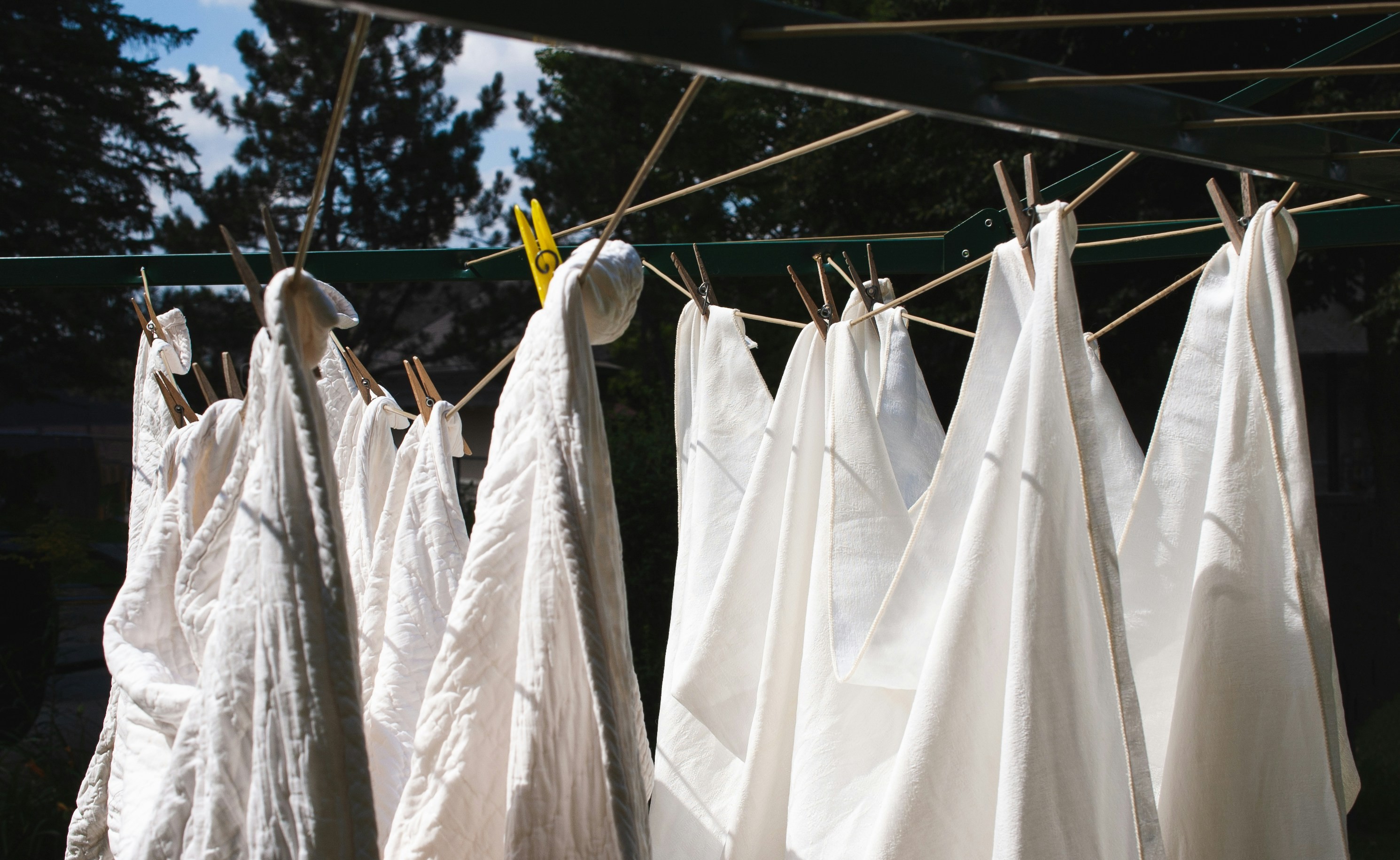 A wooden laundry brush, bar of soap and small measuring spoon on folded linen, overhead