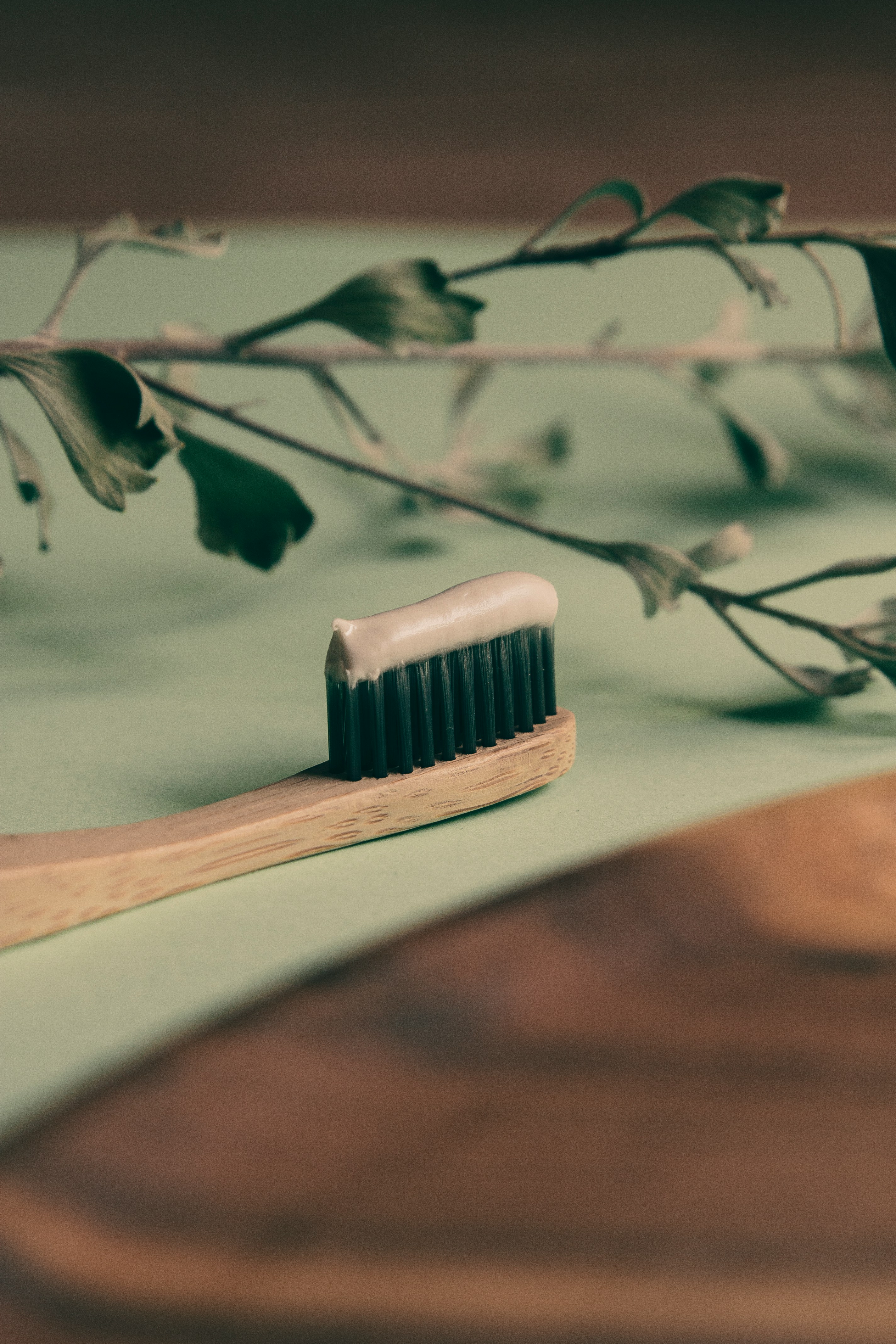 A bamboo toothbrush, small glass of water and tooth powder in a jar, simple flat lay
