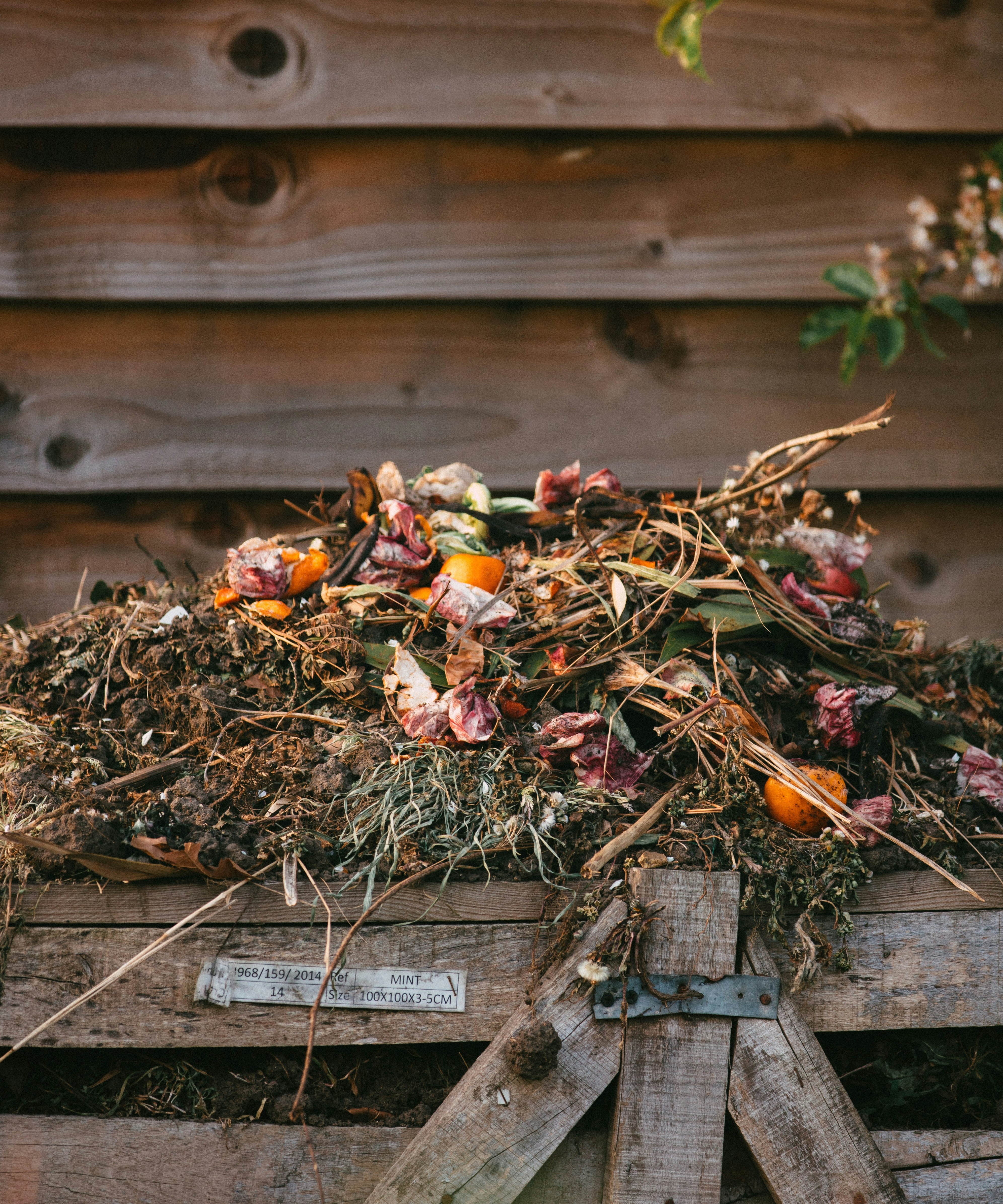 Wooden compost bin viewed from above showing layered organic material at different stages of decomposition